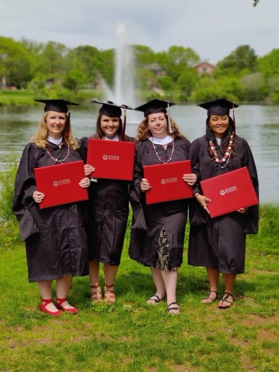 Four students hold diplomas
