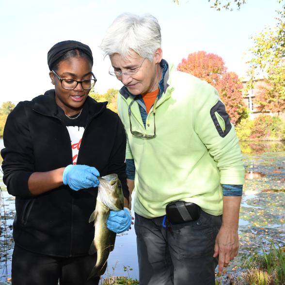 Student and professor conduct science experiment in Centennial Lake