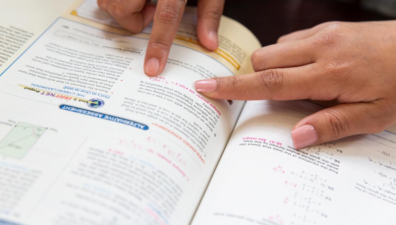 Students pointing in math textbook