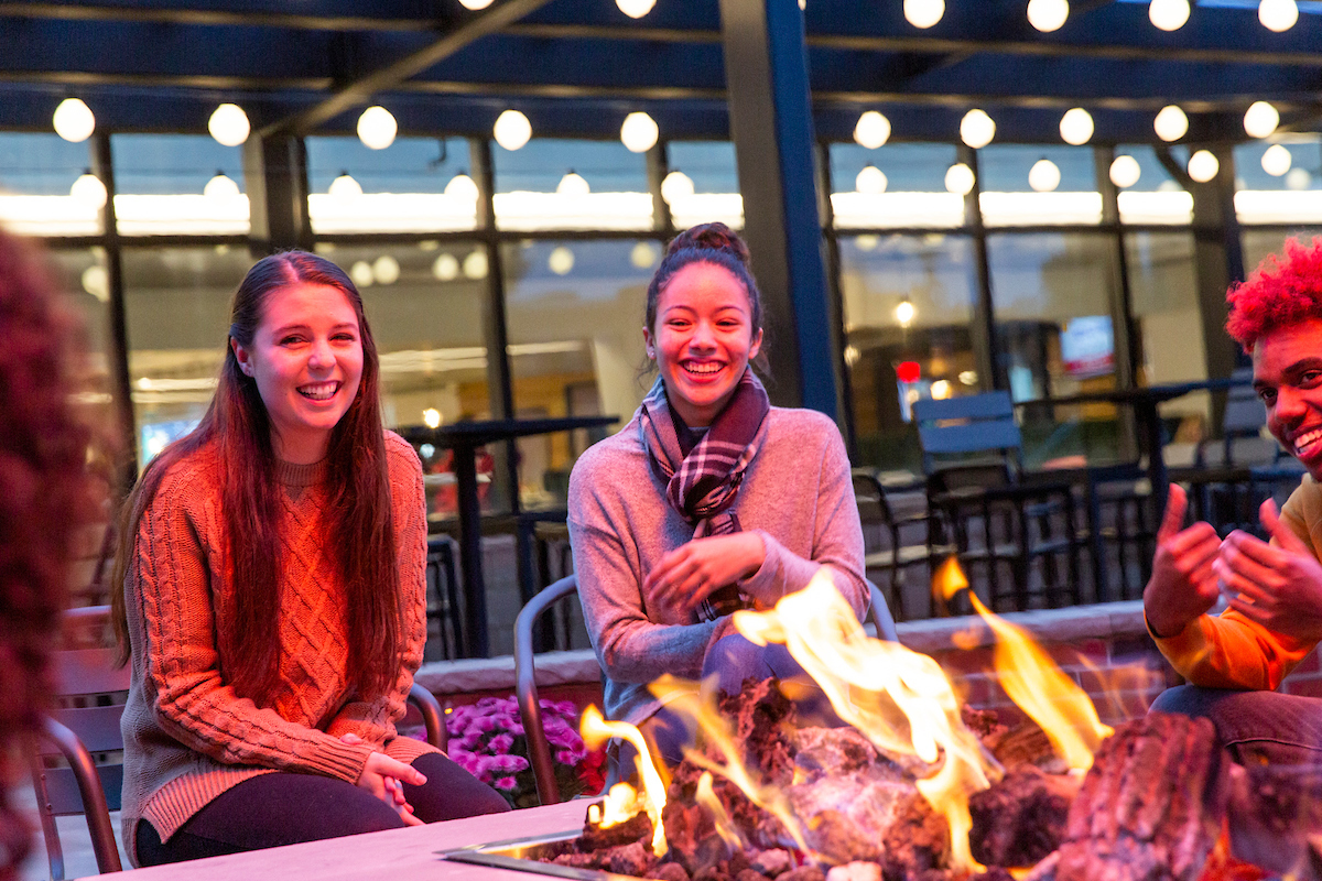 Students sit around the fire pit and laugh.