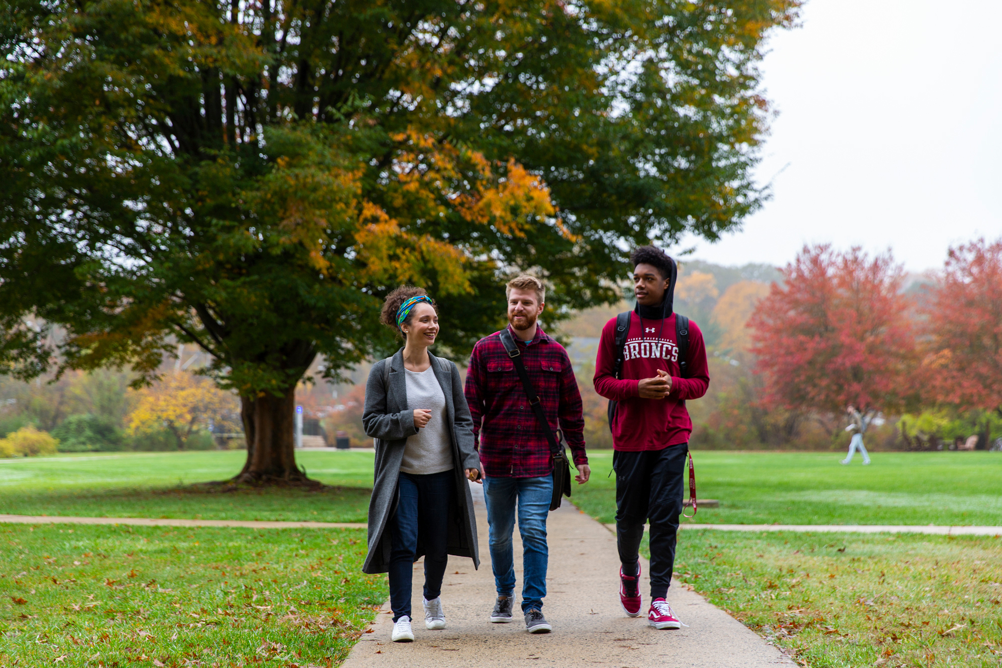 Three students walk to class in autumn