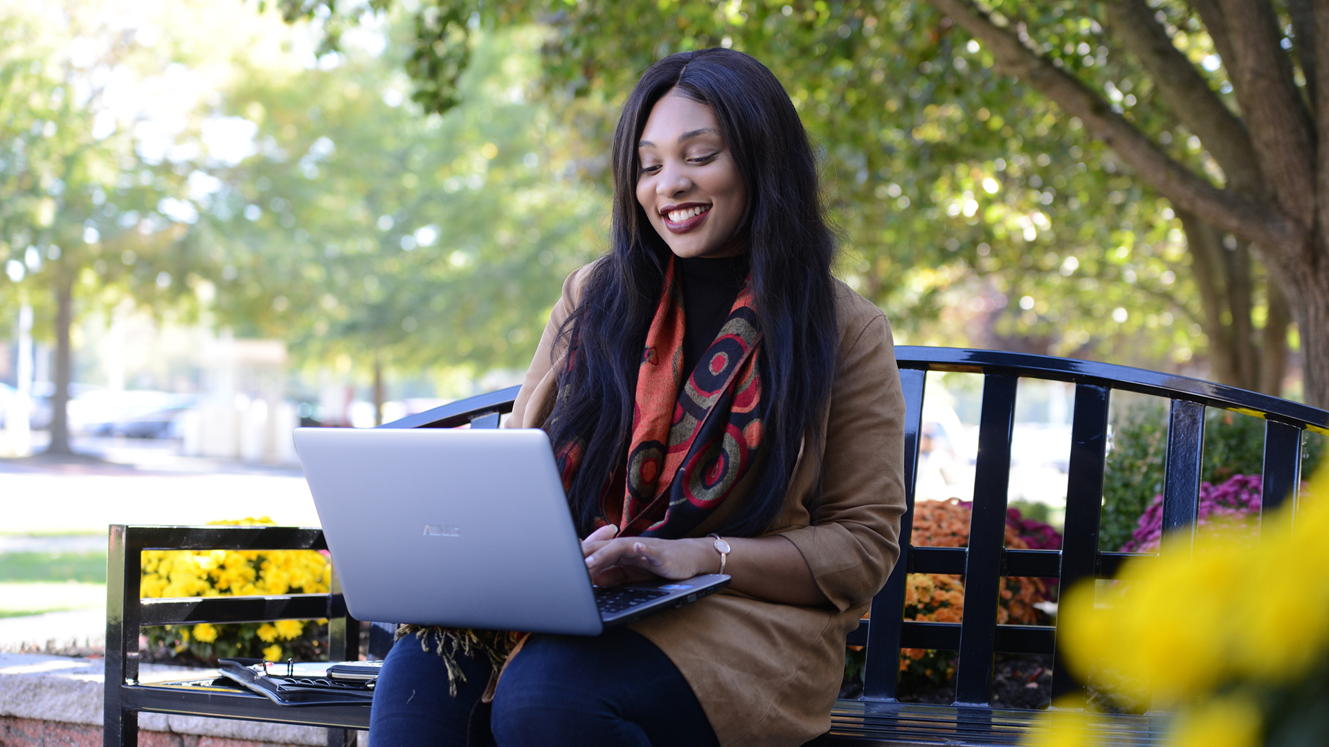 Student sits on bench working on laptop.