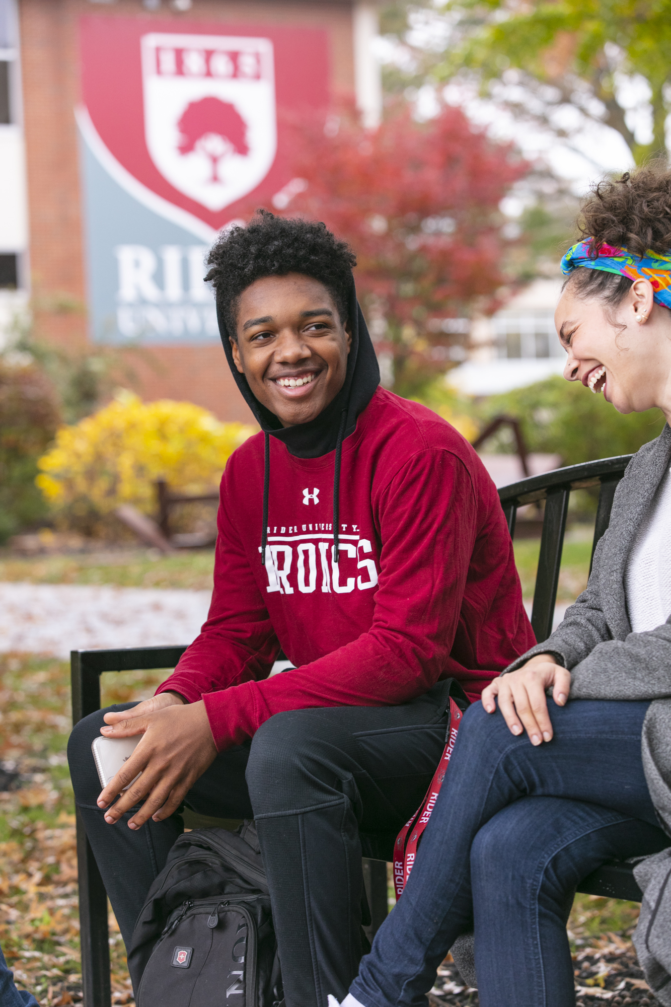 Students laugh and talk on bench