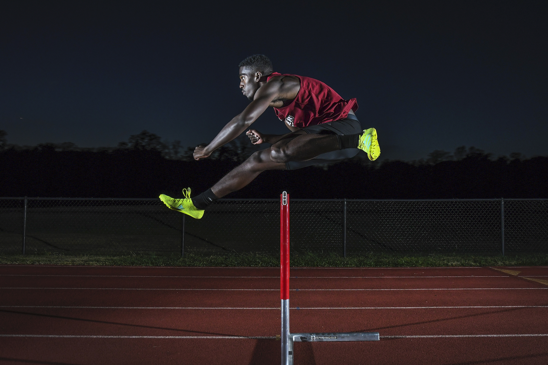 Division I athlete jumps hurdle on track