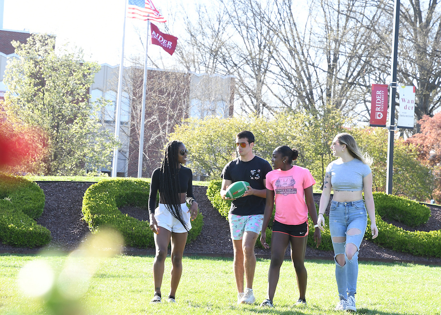 Four students walk across the campus mall