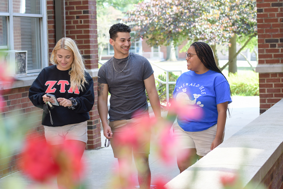 Three students walk across campus