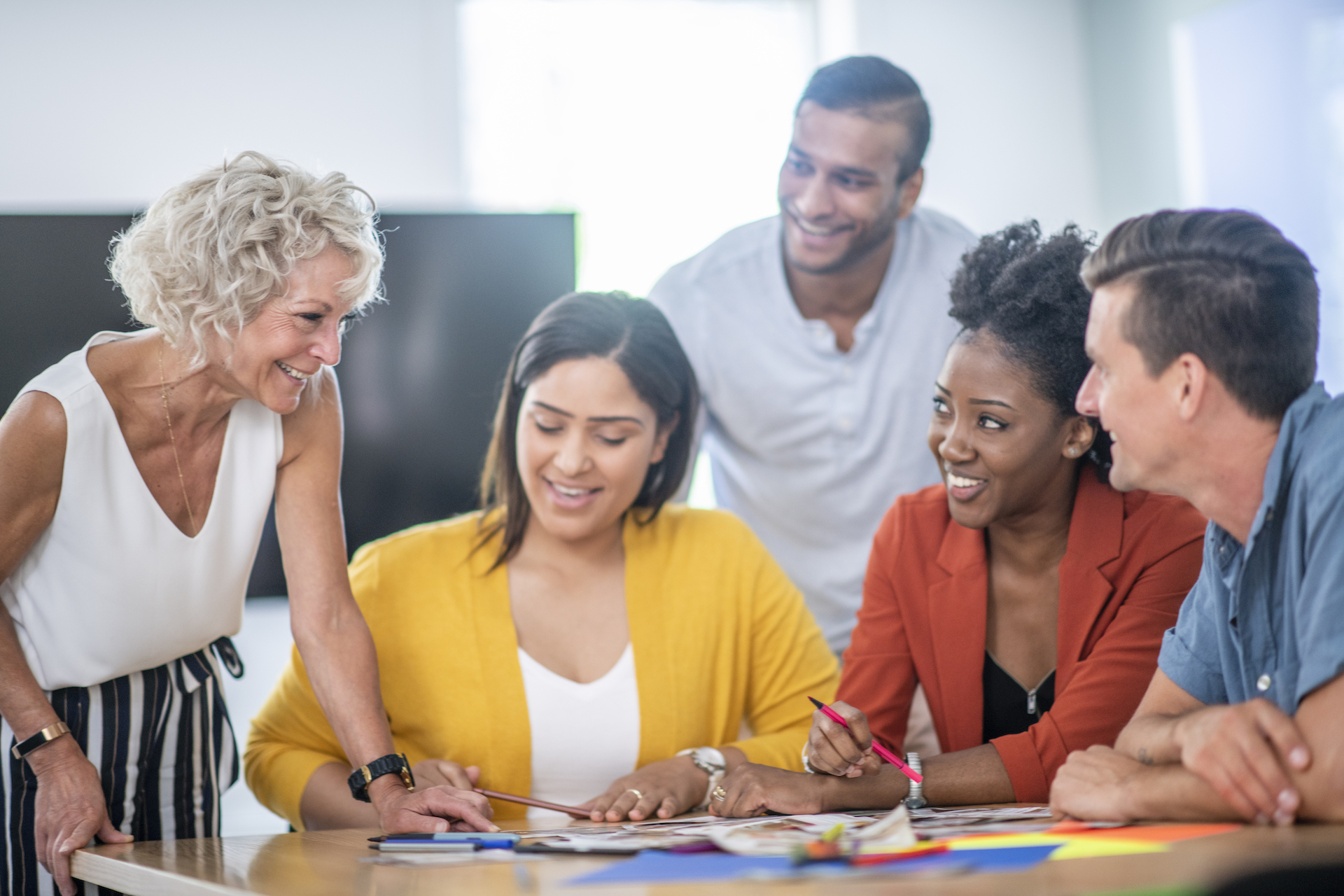 Adults gather around table, smiling