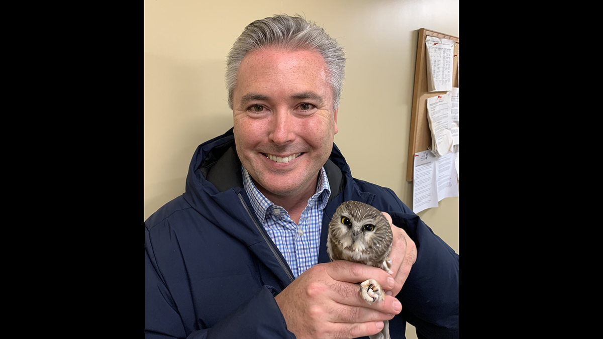 Rider alumnus Mark Bean poses holding a small owl. 