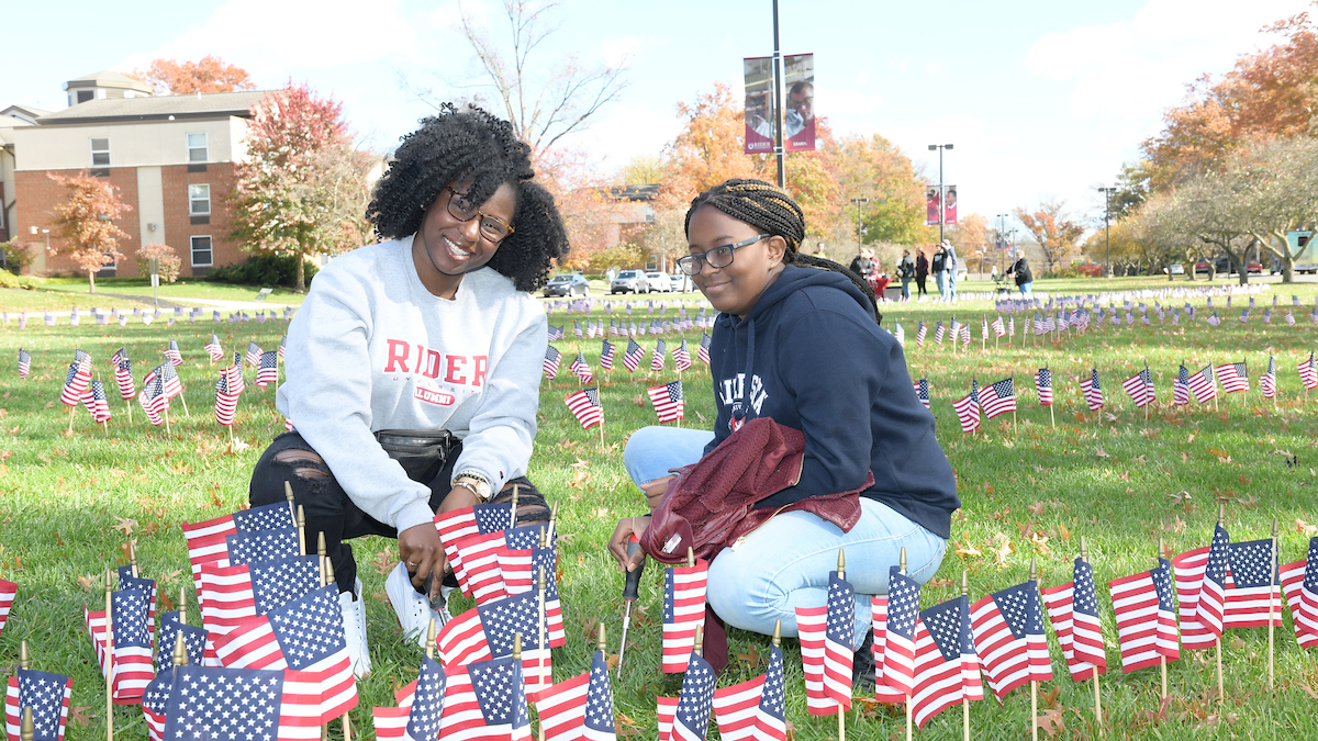 two students placing American flags on the Rider campus mall