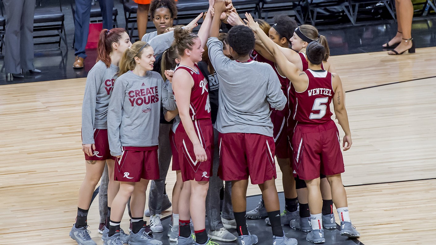 Rider women's basketball, team huddled together.