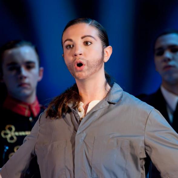 Student singing in a performance dressed as a custodian