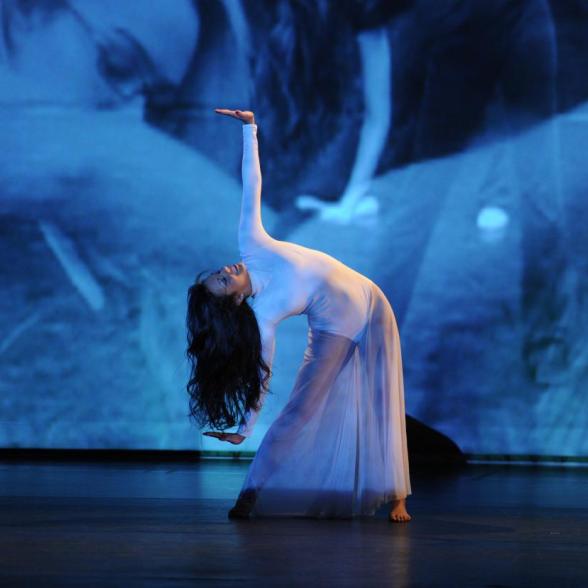 Student performing dance ensemble in blue lighting
