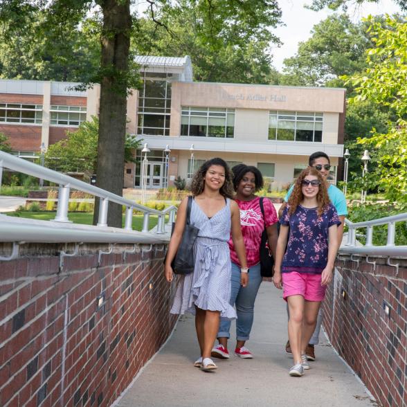 Four students walk across campus