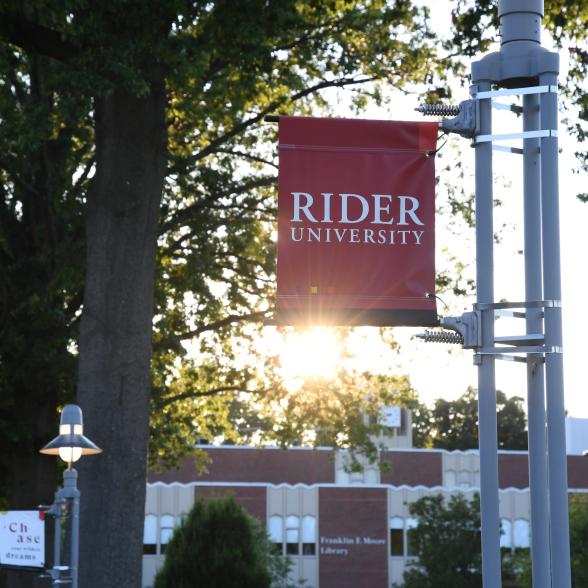 Rider sign at sunset in front of Moore library