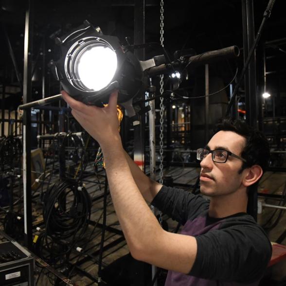 Student adjusts light on theatrical set