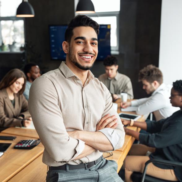 Young businessman sitting on desk and posing