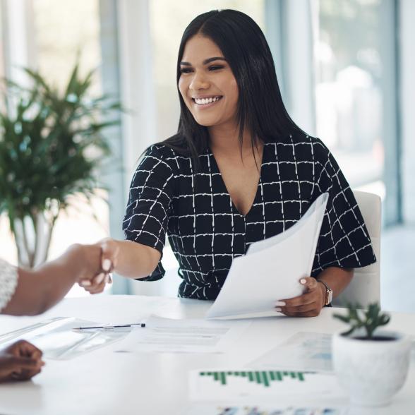 Two young businesswomen shaking hands in a modern office stock photo