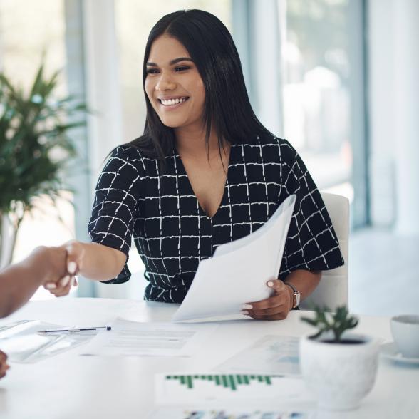 Two young businesswomen shaking hands in a modern office stock photo