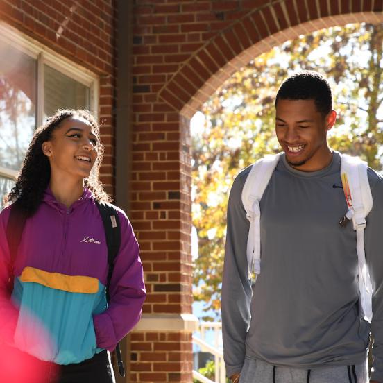 Two students walk and laugh on campus
