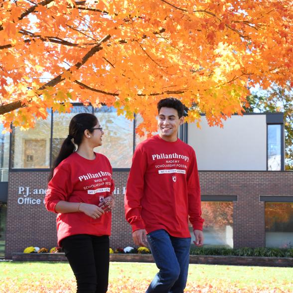 Two students walk on campus wearing red shirts