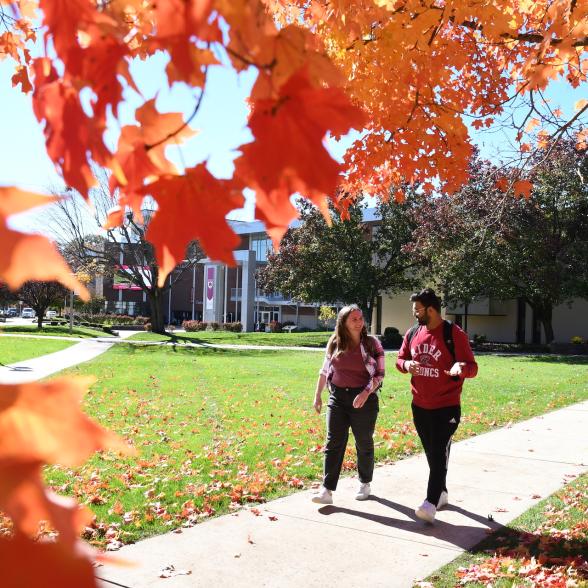 Two students walk on campus in fall