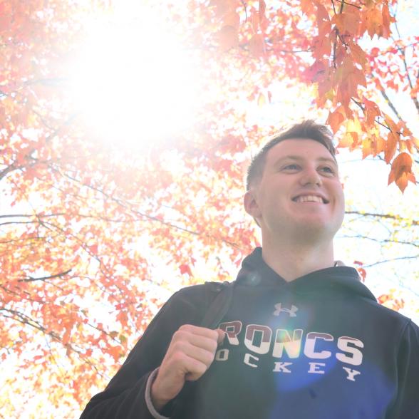 Student walks under fall leaves