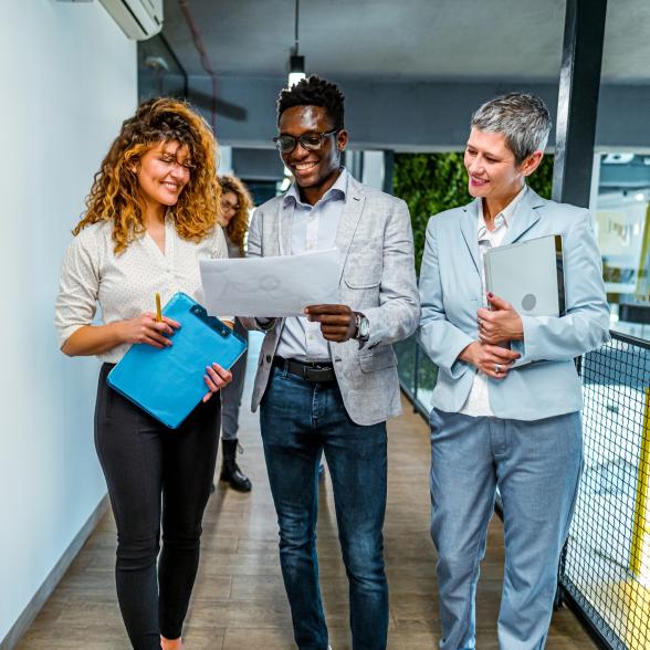 Smiling man and two women at work looking at a report together