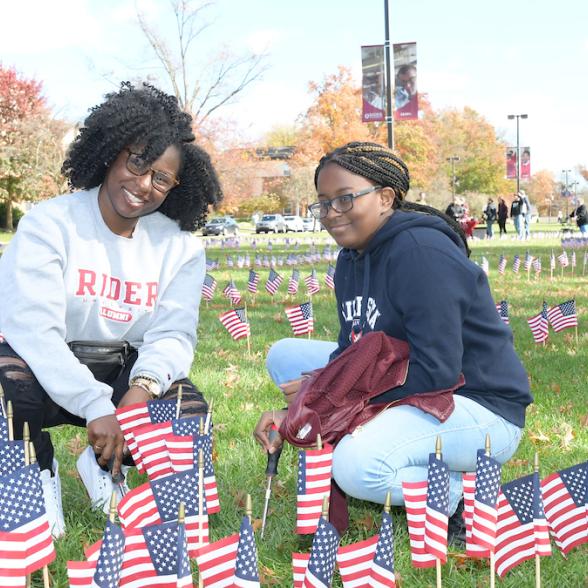 two students placing American flags on the Rider campus mall