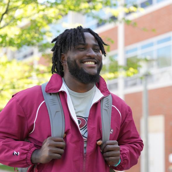 Male student in red Rider jacket walks to class