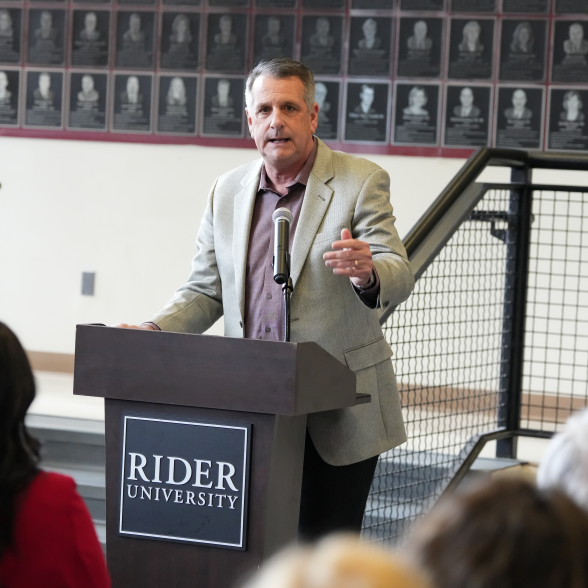 Rider University Athletics Director Don Harnum stands a podium during a press release in front of an audience