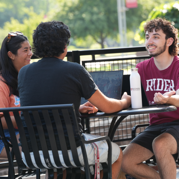Three students sit around a table studying.