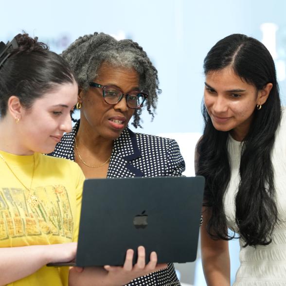 Three people look at a computer screen