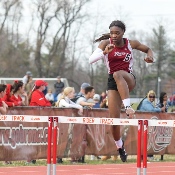 Sprinter jumps hurdles at meet.