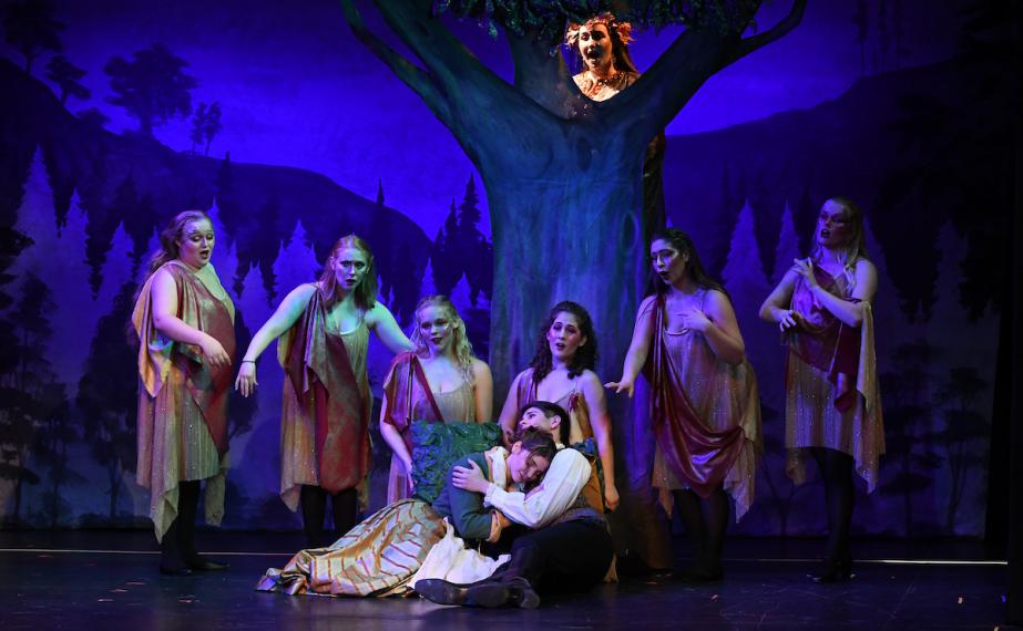 Cinderella and prince charming embrace under a tree of nymphs during the opera performance of Cinderella