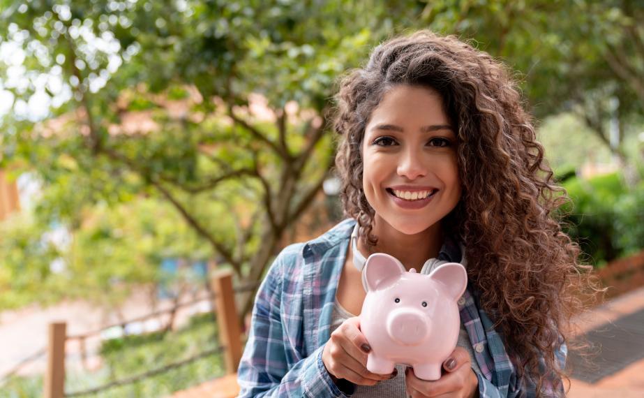 Smiling student holds piggy bank