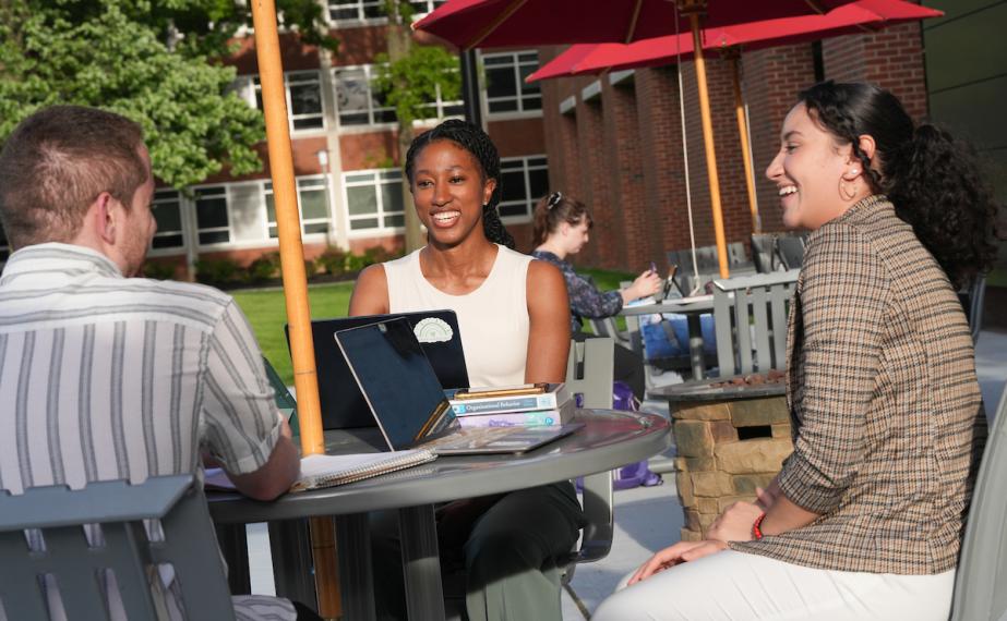 Graduate business students collaborate on a project using laptops
