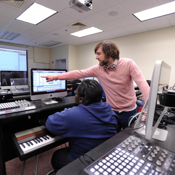 Faculty member points something out on computer to student