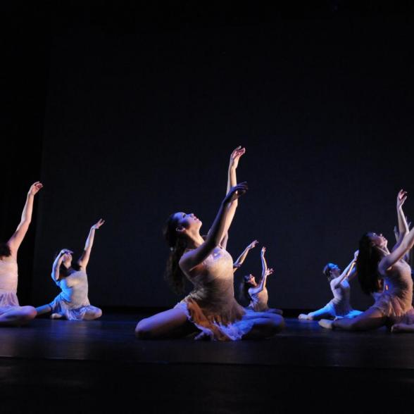 Dancers on black background illuminated in pastel lights on stage