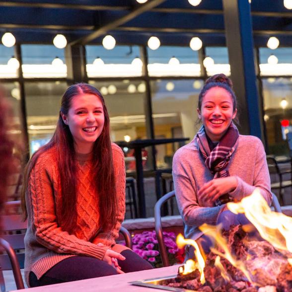 Students site around a fire and laugh.