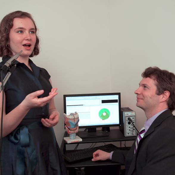 Student sings into microphone as faculty member tracks pitch in the Presser Voice Lab