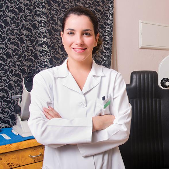 Female student in lap coat near an optometry screening share