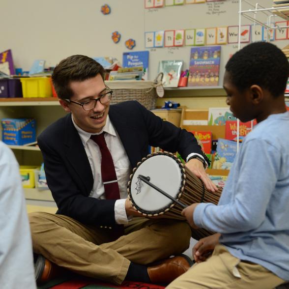 Male student works with children to play a drum
