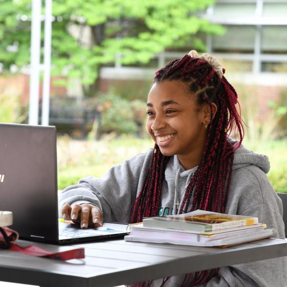 Smiling student works on laptop