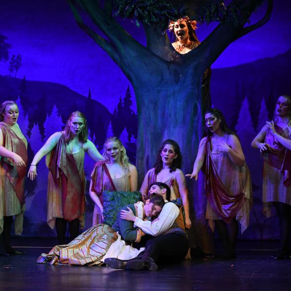 Cinderella and prince charming embrace under a tree of nymphs during the opera performance of Cinderella