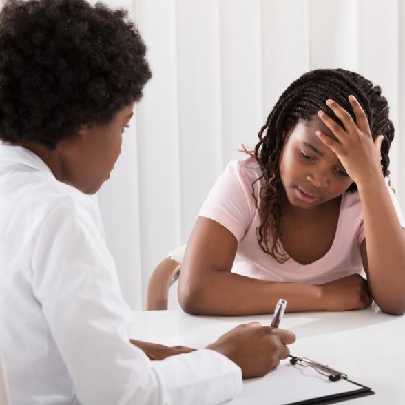 Health care provider speaks with young distressed girl