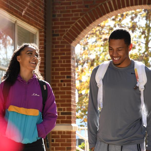 Two students walk and laugh on campus