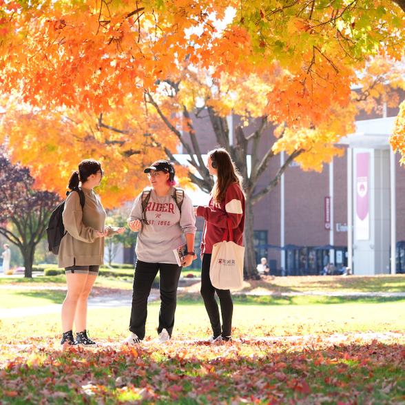 Three students talk outside the Bart Luedeke Center