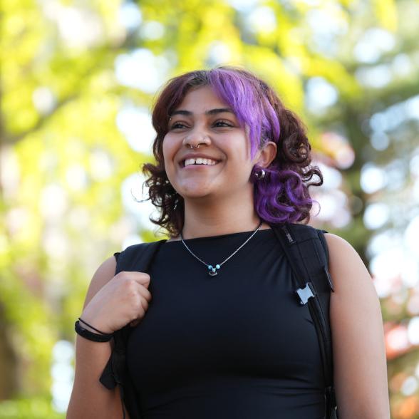 Student smiles and looks across campus