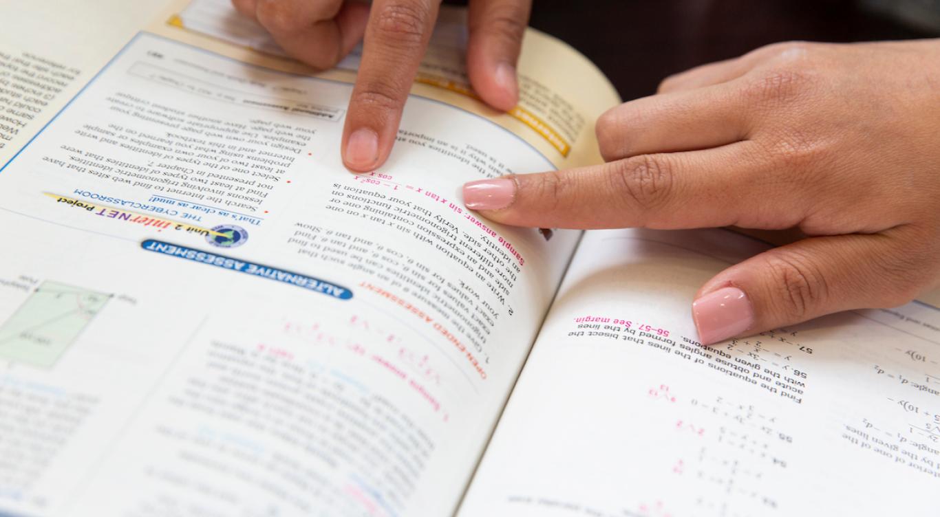 Students pointing in math textbook