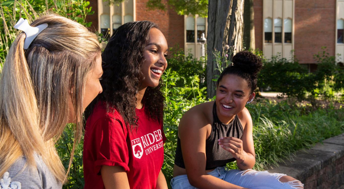 Three students talk and laugh together